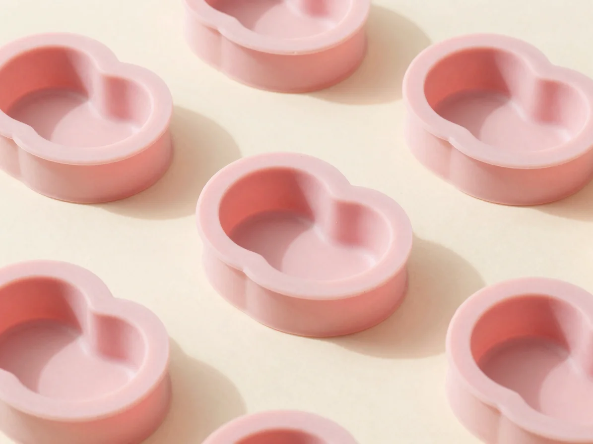 Close-up overhead product still life of pastel pink silicone molds with clean heart-shaped cavities, soft diffused studi